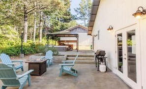 An outdoor patio with Adirondack chairs, a grill, and a covered seating area. - Sandpiper Surf by Manzanita Beach Getaway: Hot Tub, Dog-Friendly, Prime Spot (Nehalem)