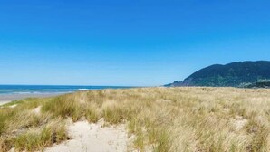 Una playa con dunas de arena y un cielo azul despejado.
