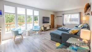 Un salón amplio con un gran ventanal, un televisor de pantalla plana, un sofá y una mesa de centro.