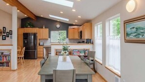 Una cocina moderna con armarios de madera, horno empotrado y comedor con una mesa larga y sillas.