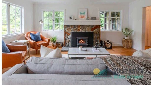 Una sala de estar acogedora con chimenea, asientos cómodos y ventanas amplias.