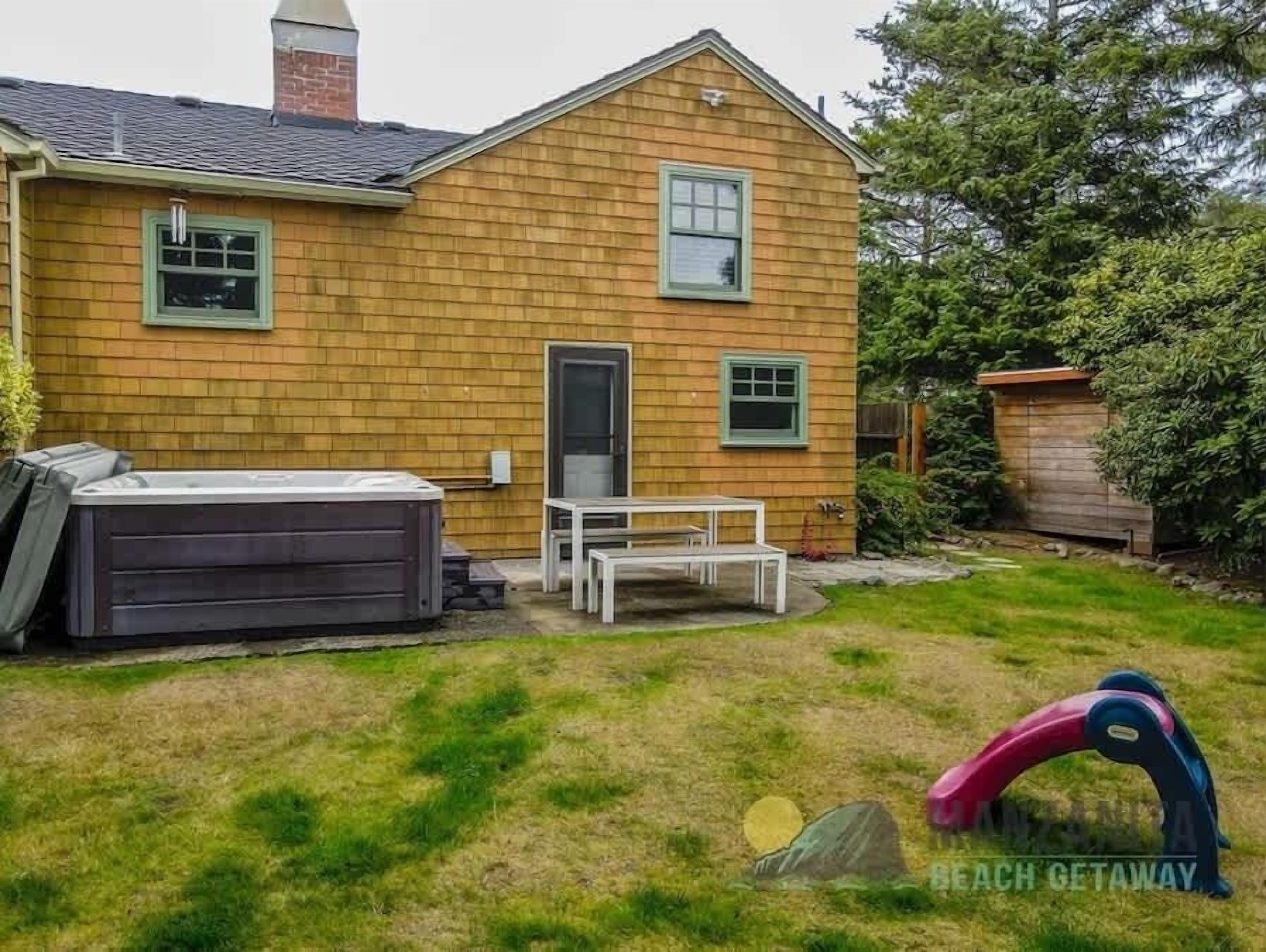 A house with a backyard, a hot tub, and a play structure.