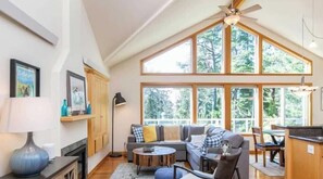 A spacious living room with a high ceiling, large windows, a fireplace, and a dining area. - The Lookout by Manzanita Beach Getaway: Blocks to the Beach & Dog Friendly (Manzanita)