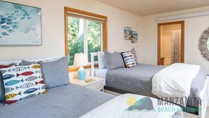 Une chambre avec deux lits, une fenêtre et des œuvres d’art accrochées aux murs.