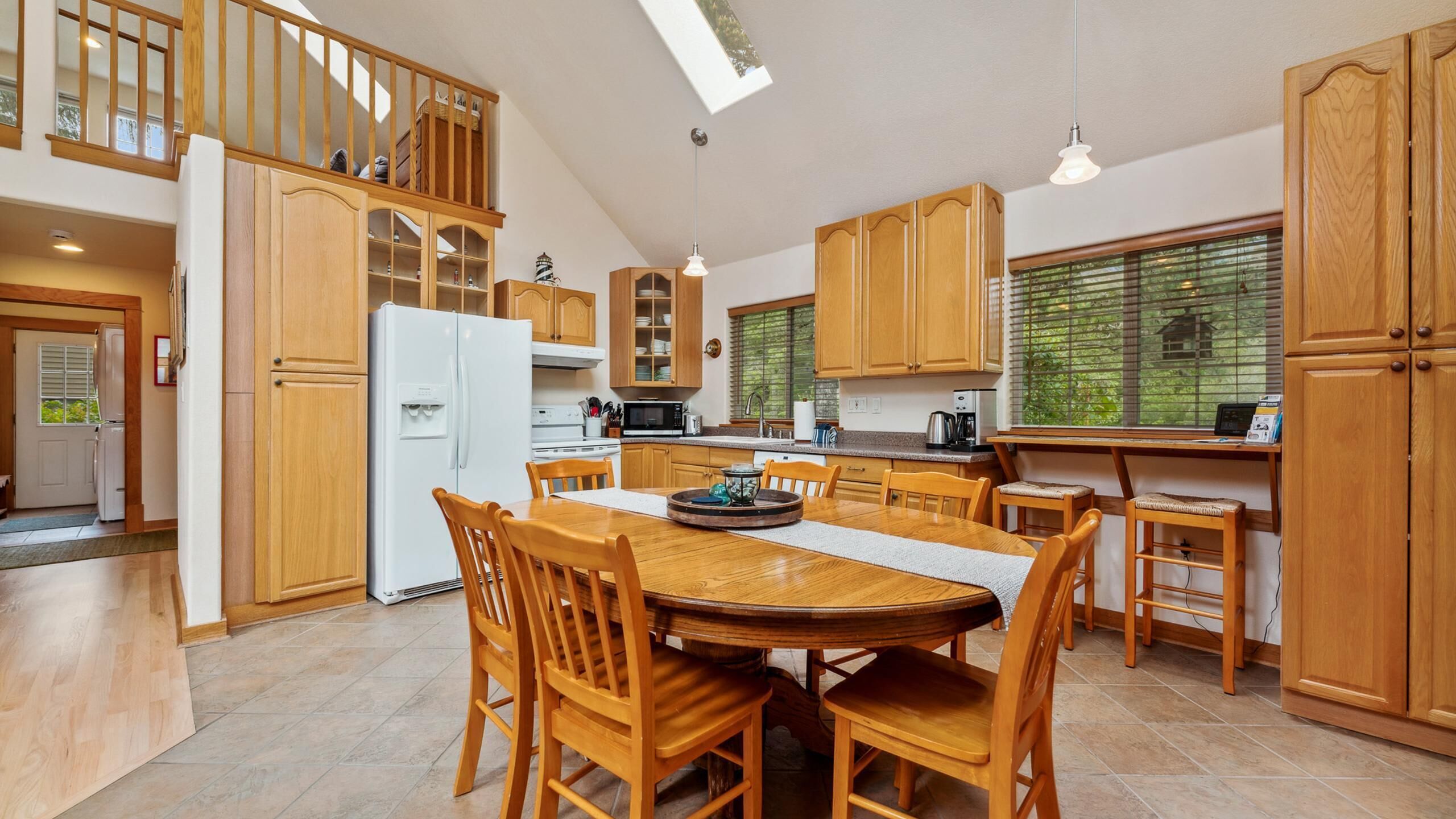 A spacious kitchen with wooden cabinets, a central island, and a dining area with wooden chairs.