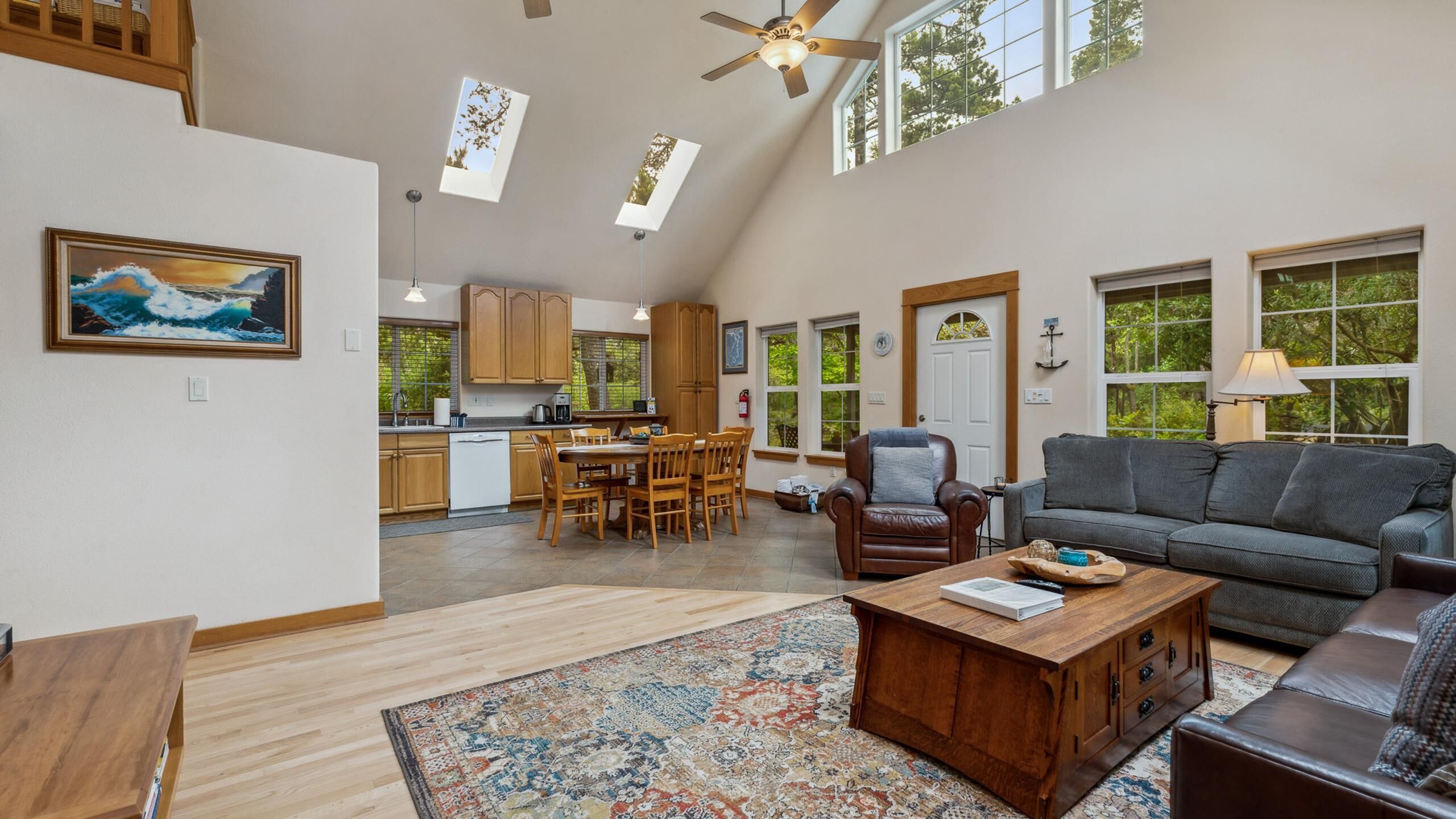 A spacious living area with a high ceiling, a dining area, and a kitchen.