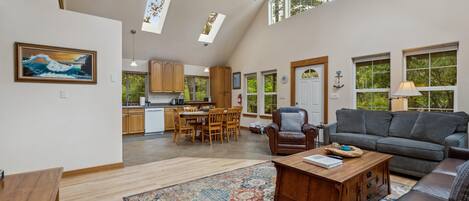 A spacious living area with a high ceiling, a dining area, and a kitchen.