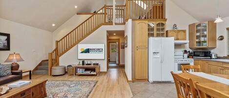 A spacious living area with a wooden staircase, a kitchen with modern appliances, and a dining area.