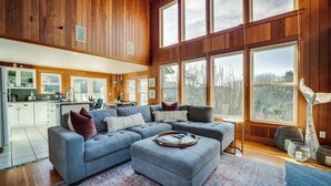 A spacious living room with a large sectional sofa, a dining area, and a kitchen.