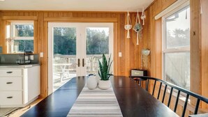 A modern kitchen with wooden paneling, a large dining table, and potted plants.