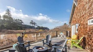 A wooden deck with outdoor seating and a fire pit.