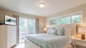 Een slaapkamer met een bed, nachtkastje, kaptafel en een televisie waarop 'Manzanita Beach Getaway' staat.