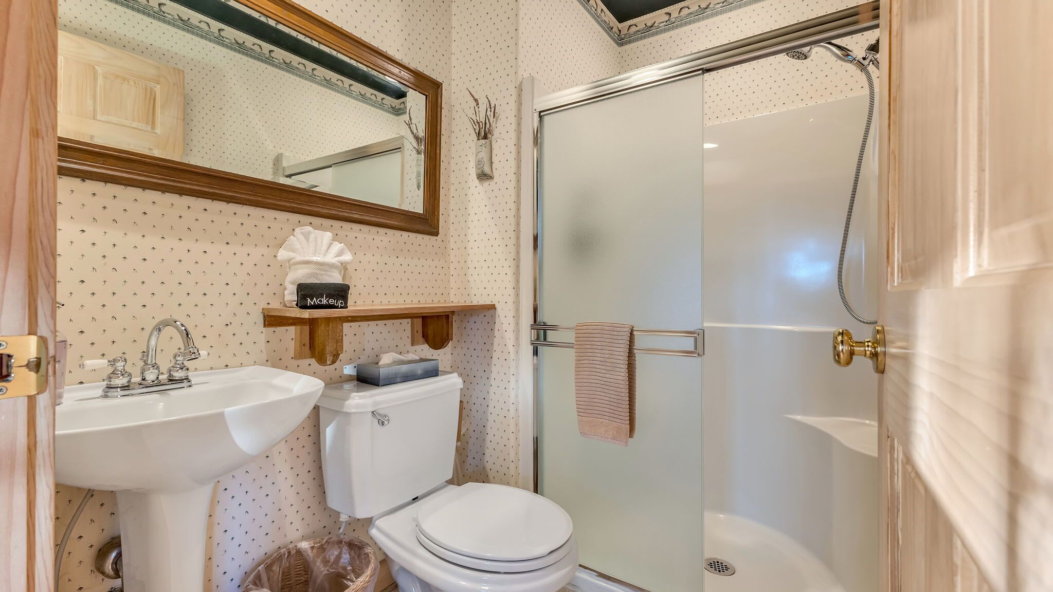 Un baño con lavamanos, inodoro y ducha con mampara de vidrio.