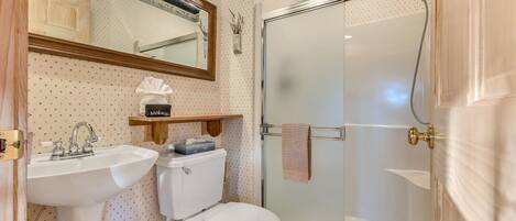 Un baño con lavamanos, inodoro y ducha con mampara de vidrio.