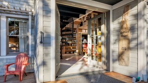Fachada de madera con puerta corredera de vidrio que da a una biblioteca llena de estanterías.