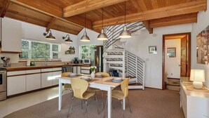 Eine moderne Küche mit Holzbalken, einem Essbereich mit gelben Stühlen und einer Wendeltreppe.