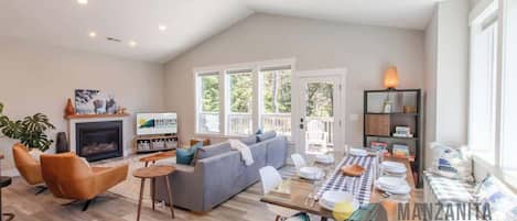 Ein geräumiges Wohnzimmer mit Kamin, einer Couch, einem Esstisch und einem Fernseher.