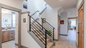 A modern interior with a staircase, wooden cabinets, and a kitchen area.