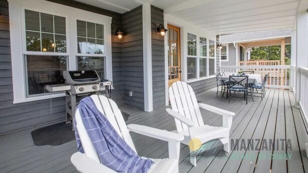 Une véranda avec des fauteuils Adirondack blancs, un barbecue et une table à manger avec des chaises.
