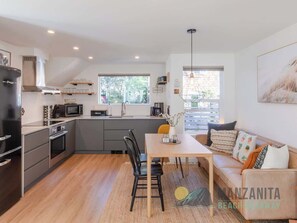 A modern kitchen with a dining area, a sofa, and a coffee machine.