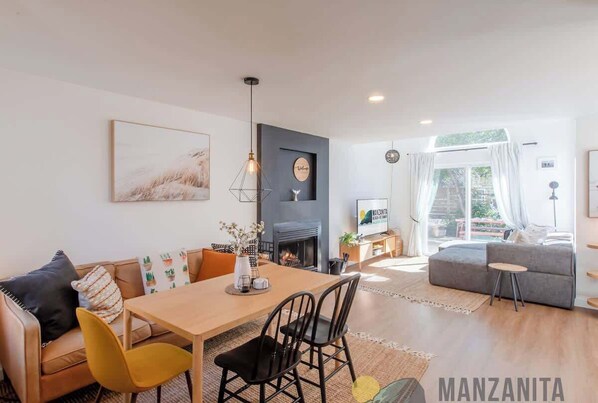 A modern living room with a fireplace, a dining area, and a sofa.