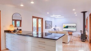 A modern kitchen with a large island, white cabinetry, and a dining area with a sofa and table.