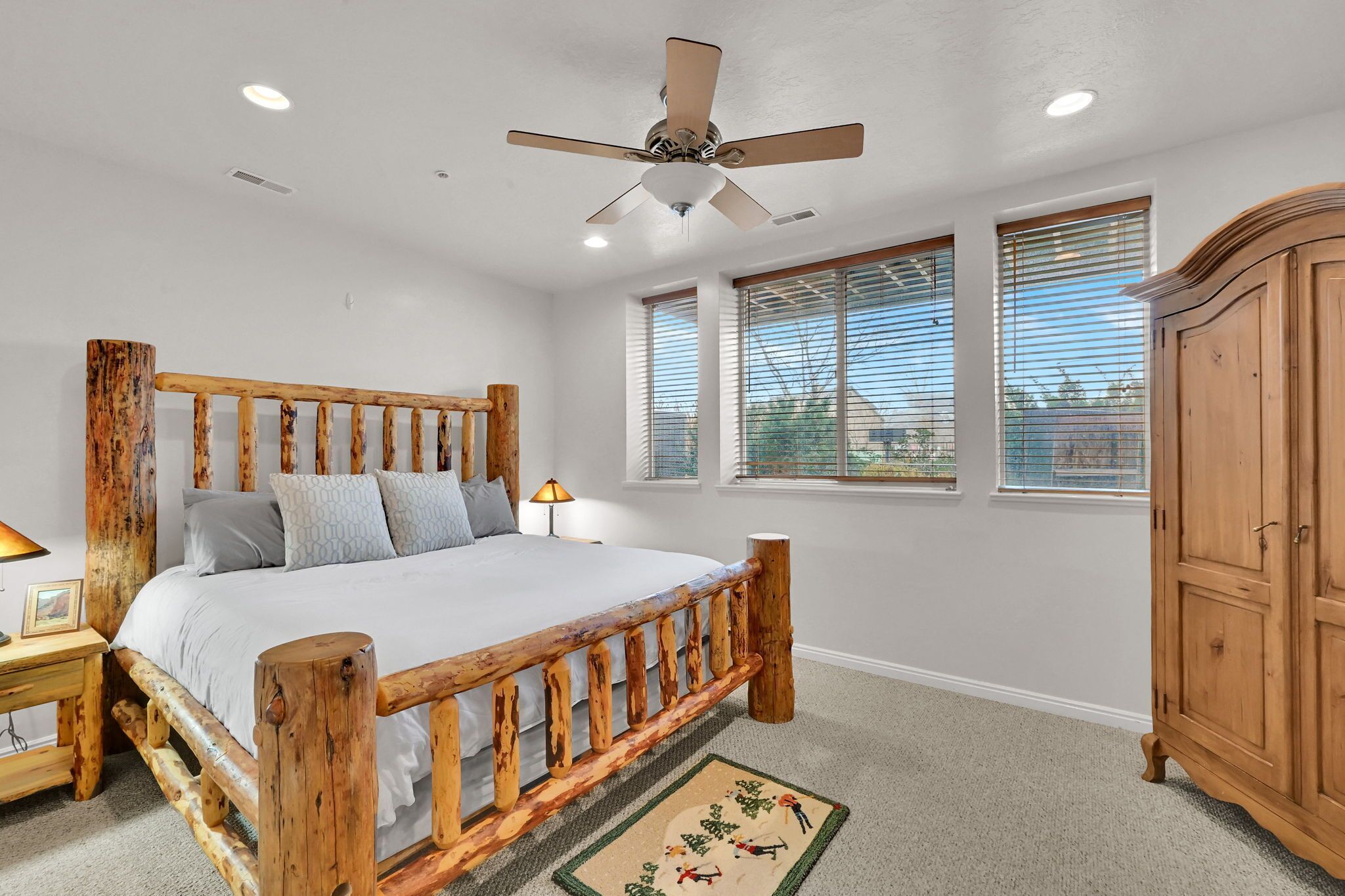 A bedroom with a wooden bed, a ceiling fan, and a nightstand with a lamp.