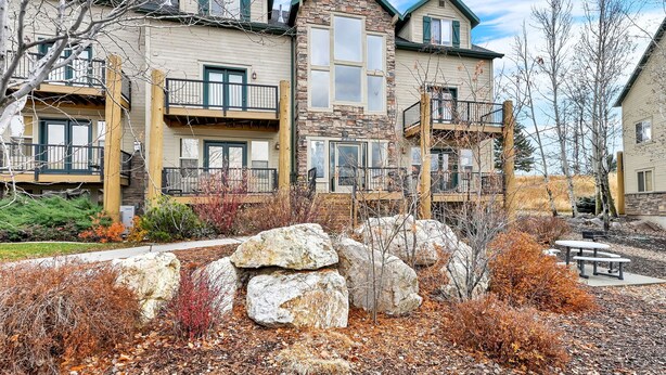 A multi-story building with balconies, stone facade, and a landscaped front yard with rocks and shrubs. - MH603 | Pinecone Retreat: Adventure Awaits in Eden, UT! (Eden)