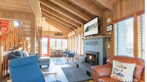 Ein gemütliches Interieur mit Kamin, bequemen Sitzgelegenheiten und einer Holzbalkendecke.