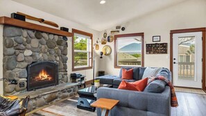 A cozy living room with a stone fireplace, a comfortable sofa, and a view of the outdoors.