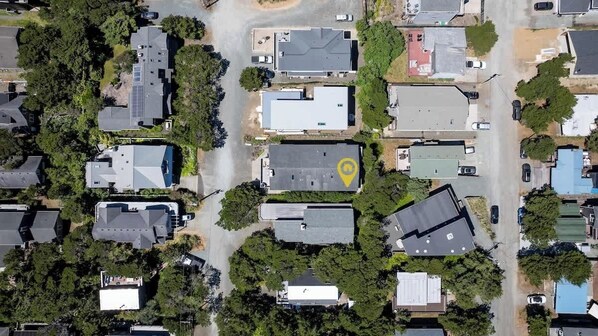 An aerial view of a residential area with houses, roads, and a yellow location marker.