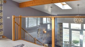 A spacious room with a wooden staircase, a large window with a view, and a chandelier. - A seaside sanctuary perched on the shores of Westward Ho. (Westward Ho!)