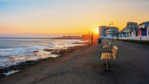 A seaside promenade with benches, a railway track, and buildings along the shore. - A seaside sanctuary perched on the shores of Westward Ho. (Westward Ho!)