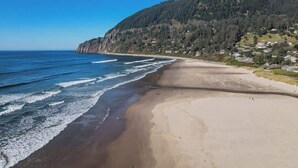 A beach with a clear view of the ocean and a forested hillside in the background. - Sea Star by Manzanita Beach Getaway: 3BR Family & Dog-Friendly Near Beach (Manzanita)