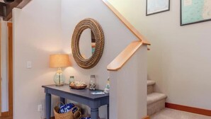 A staircase with a wooden handrail, a blue console table with a lamp, and a wall-mounted rope decoration. - Sea Star by Manzanita Beach Getaway: 3BR Family & Dog-Friendly Near Beach (Manzanita)