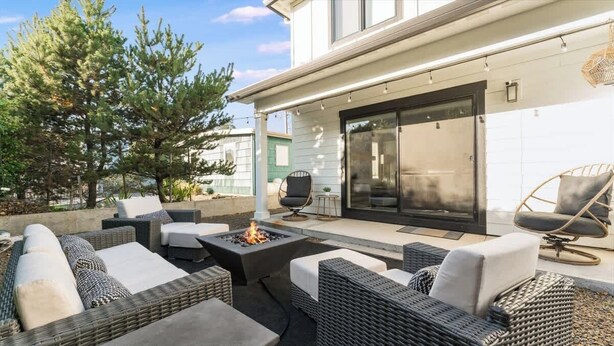 Un patio con mobiliario de mimbre, un hogar y un ventanal corredera que da a un espacio cubierto.