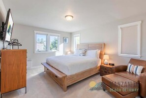 Une chambre à coucher avec un lit en bois, des tables de chevet, un canapé, une télévision et une fenêtre.