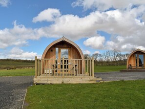 A wooden cabin with a balcony, a dining table, and a chair. - 2 bedroom accommodation in Corney, near Millom (Corney, near Millom)