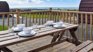Una terraza de madera con una mesa lista para comer, con vistas a un paisaje idílico.