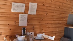 Un interior de madera con una mesa para dos, un control remoto, un hervidor y un cubo de basura.