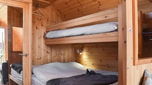 Un dormitorio con literas de madera, una puerta, un escritorio pequeño y una mesita de noche.