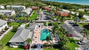 An aerial view of a resort with multiple buildings, a swimming pool, and a parking area.