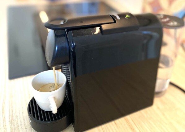 Une machine à café avec un récipient pour recueillir le café, branchée à une prise électrique.