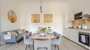 A modern kitchen with a dining area, a sofa, and a wall-mounted mirror.