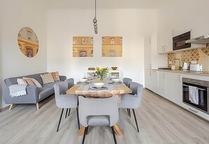 Una cocina moderna con comedor, un sofá y un espejo montado en la pared.
