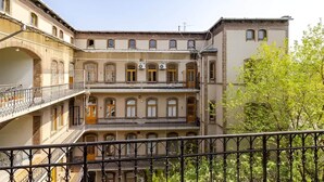 A multi-story building with balconies, a staircase, and a tree in the foreground.