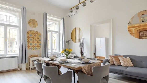 A modern dining area with a table set for four, surrounded by grey chairs.
