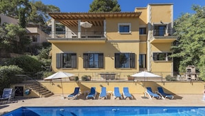 A two-story building with a swimming pool, sun loungers, and outdoor furniture. - Villa Can Oronella by Balearic Villas (Pollensa)