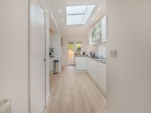 Une cuisine moderne dotée d’une verrière, de meubles blancs et offrant une vue sur l’extérieur.