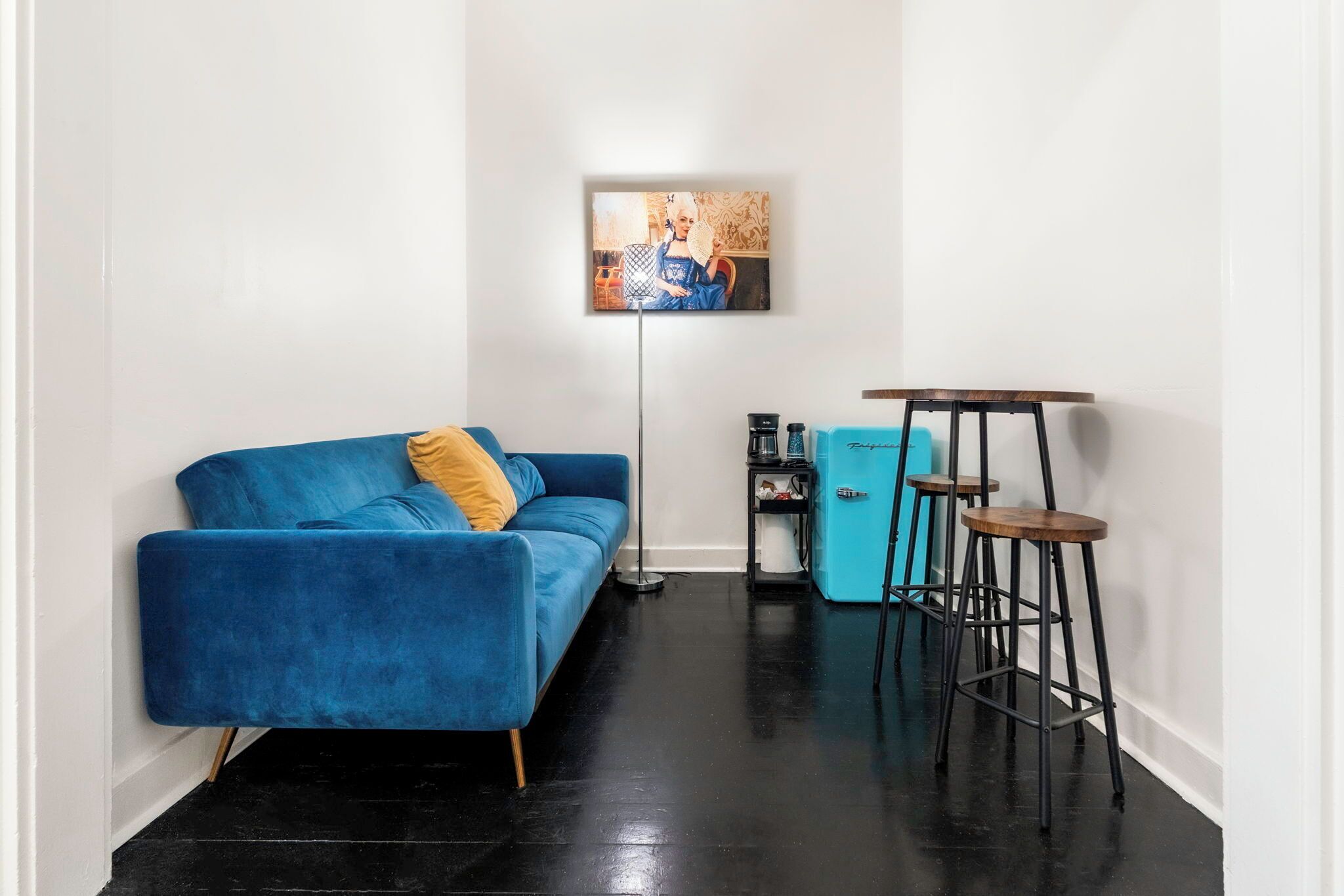 A modern living room with a blue sofa, a coffee table, a floor lamp, and a blue cabinet.
